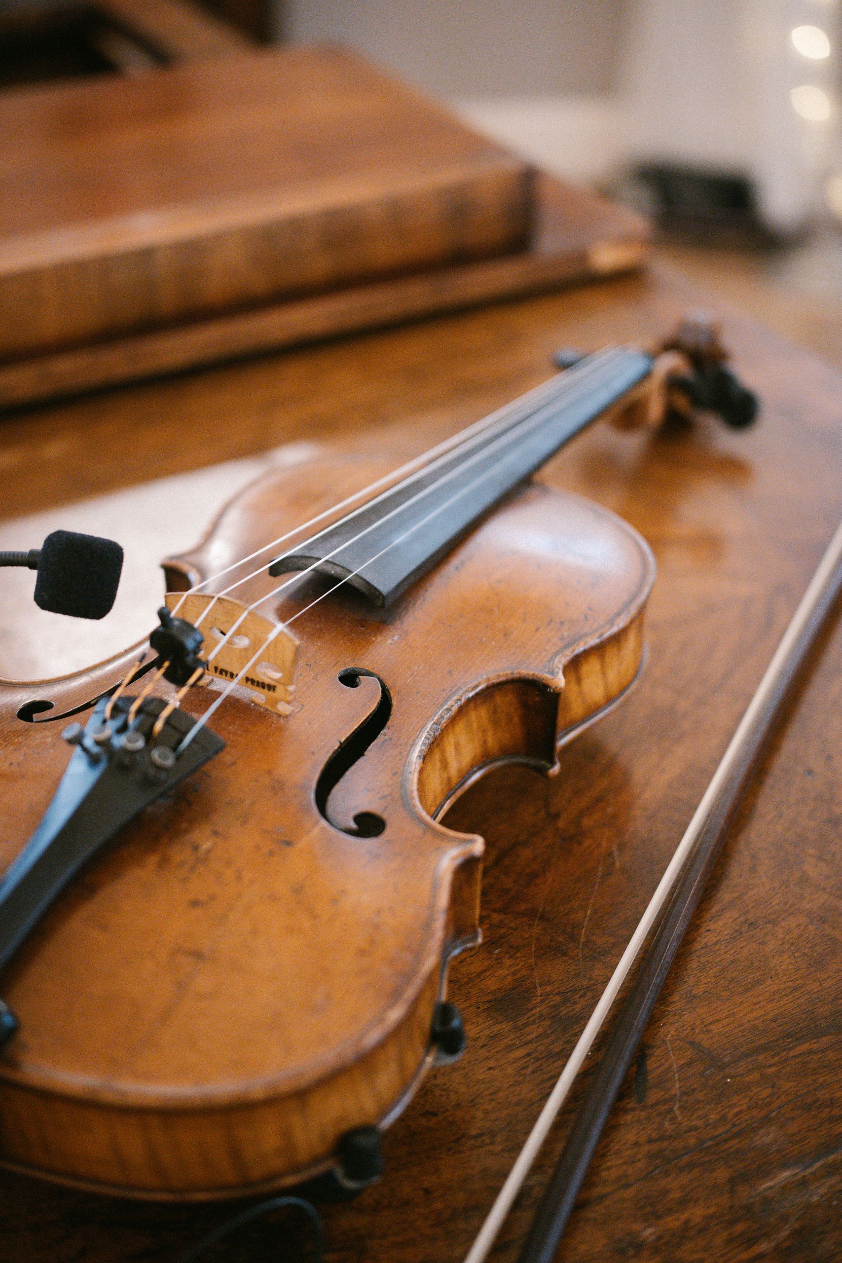 Elegant vintage violin resting on a rustic wooden table, emphasizing its classic design.